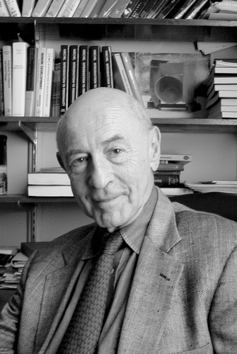 Dr. Walter Mischel smiling at his desk.